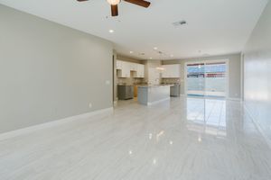 Spacious open concept room with glossy white tile floors and modern recessed lighting.