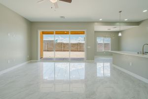 Bright open living space with reflective tile floors, sliding glass doors, and modern kitchen view.