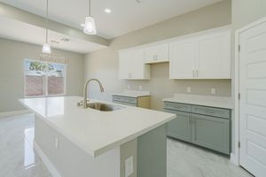 Minimalist kitchen design with white countertops, grey cabinets, and pendant lighting.