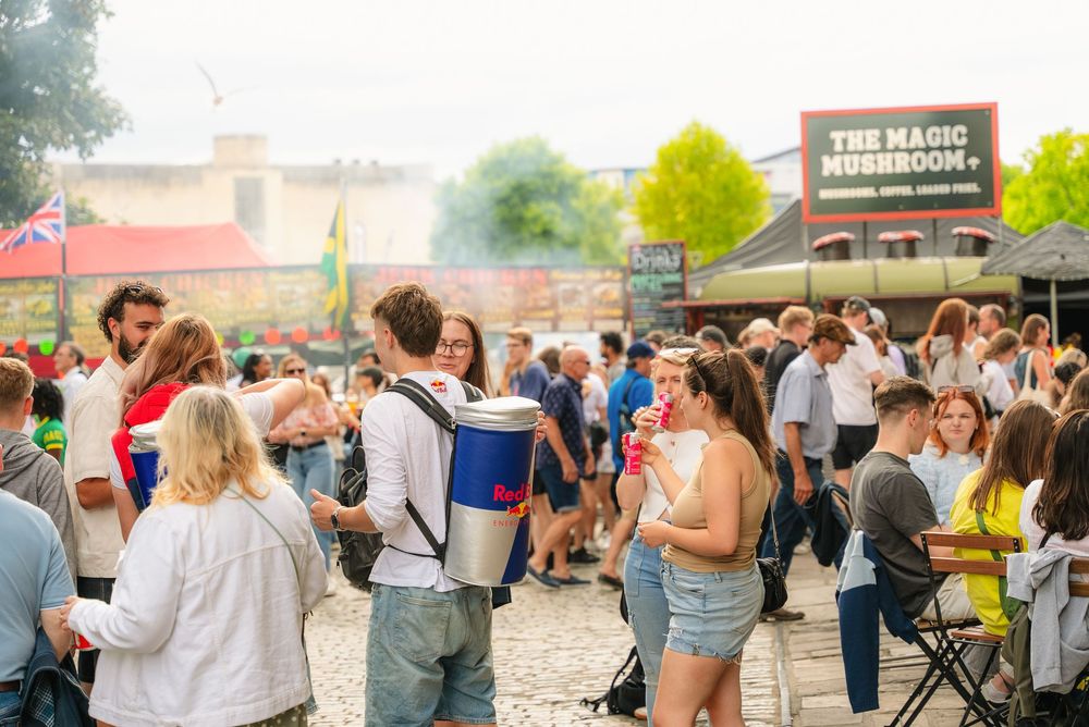 People enjoying a lively outdoor event with food trucks and gathering spaces at sunset.