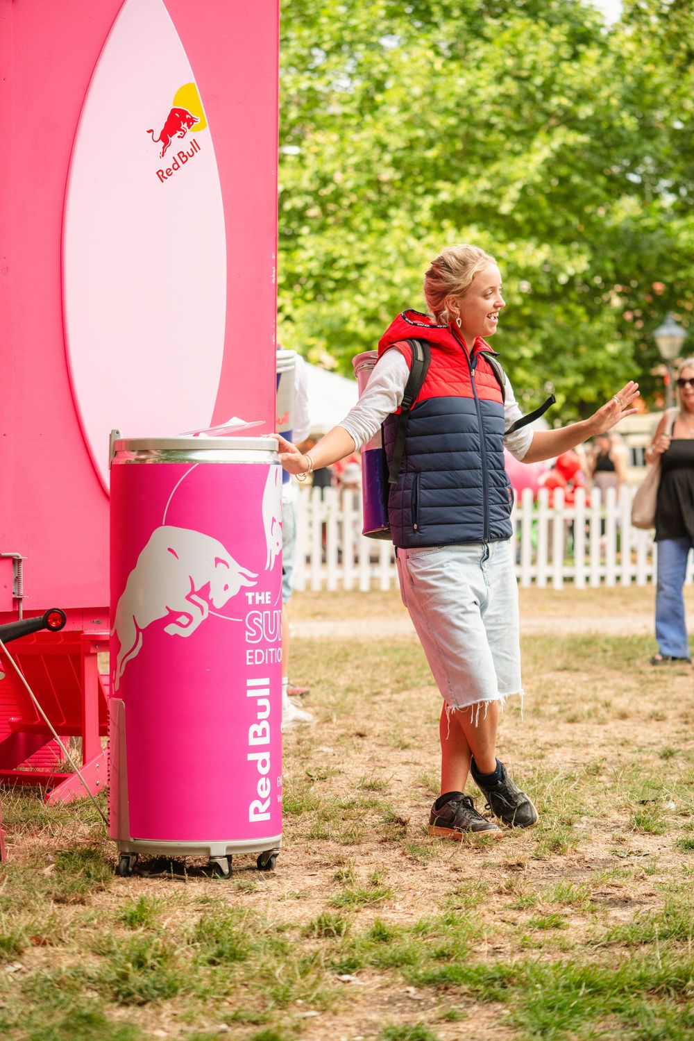 A sequence of images showing someone falling behind large pink Red Bull branded displays at an outdoor event.