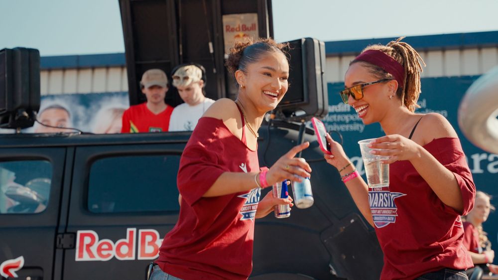 Athletes in red jerseys share refreshing beverages during a break at a sports event.