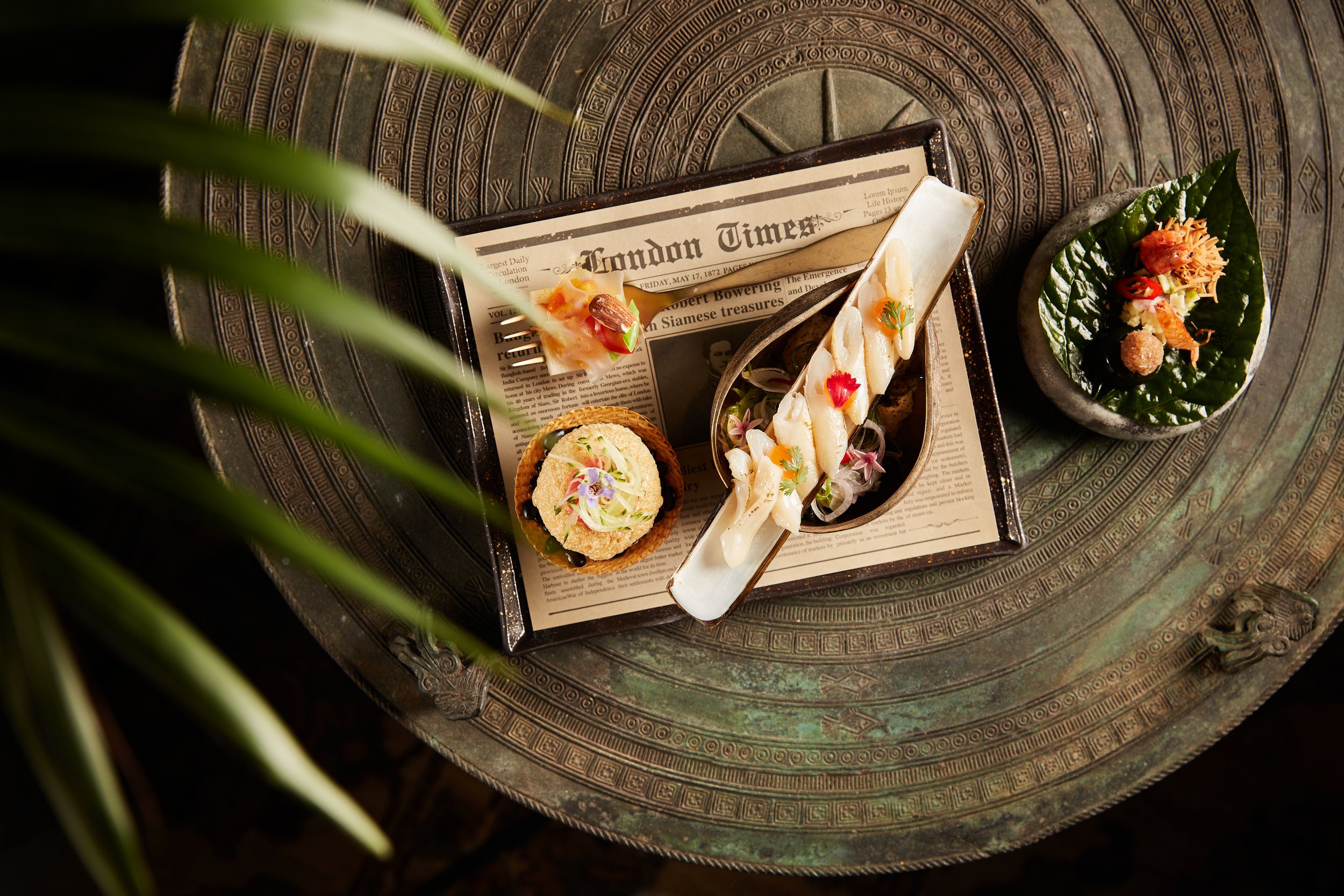 Elegant appetizers on a wooden tray with London Times branding, featuring decorative bites and garnishes on a rustic table.