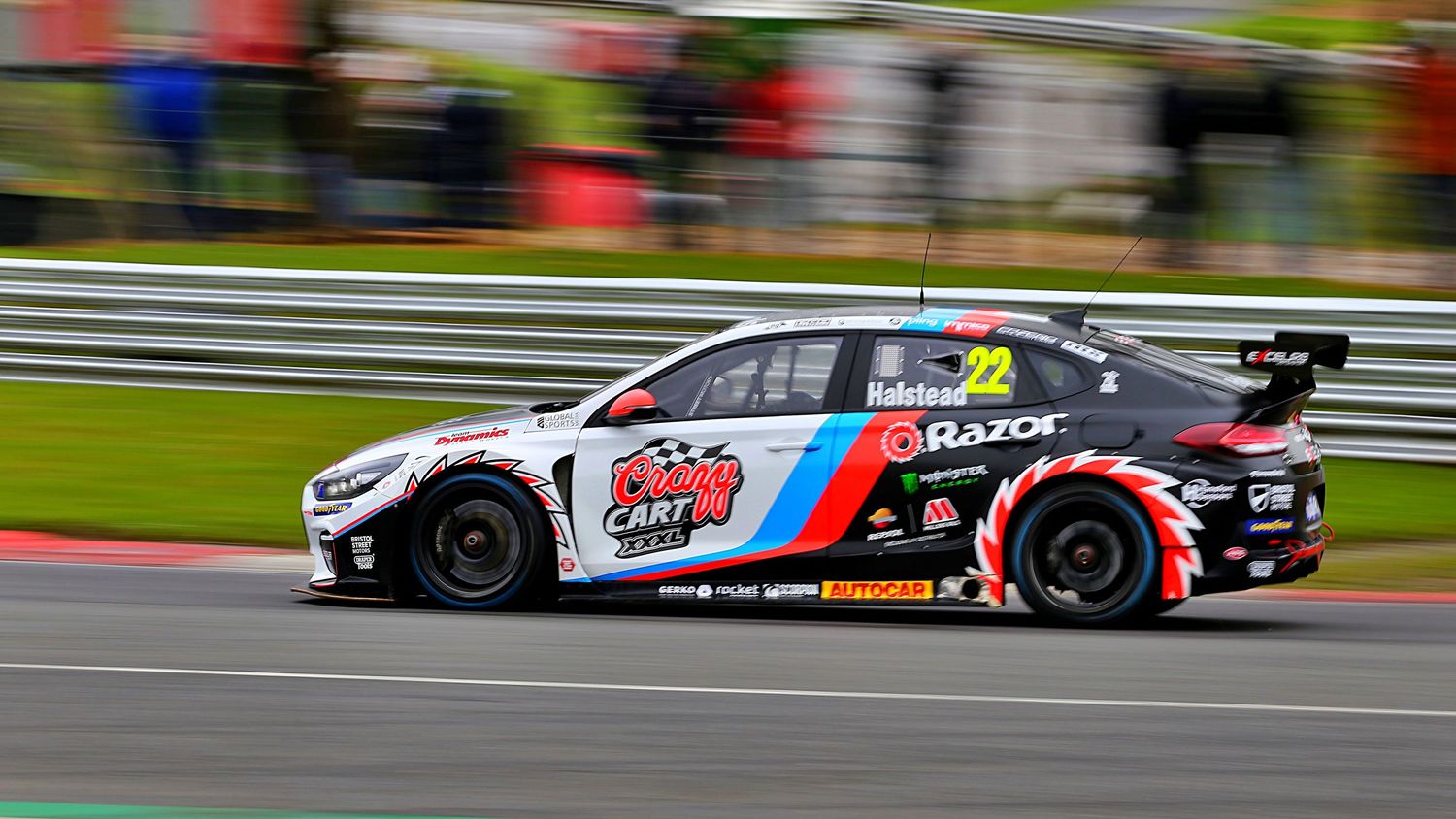 BTCC race car number 22 with Razor branding speeds along a circuit at a British Touring Car Championship event.