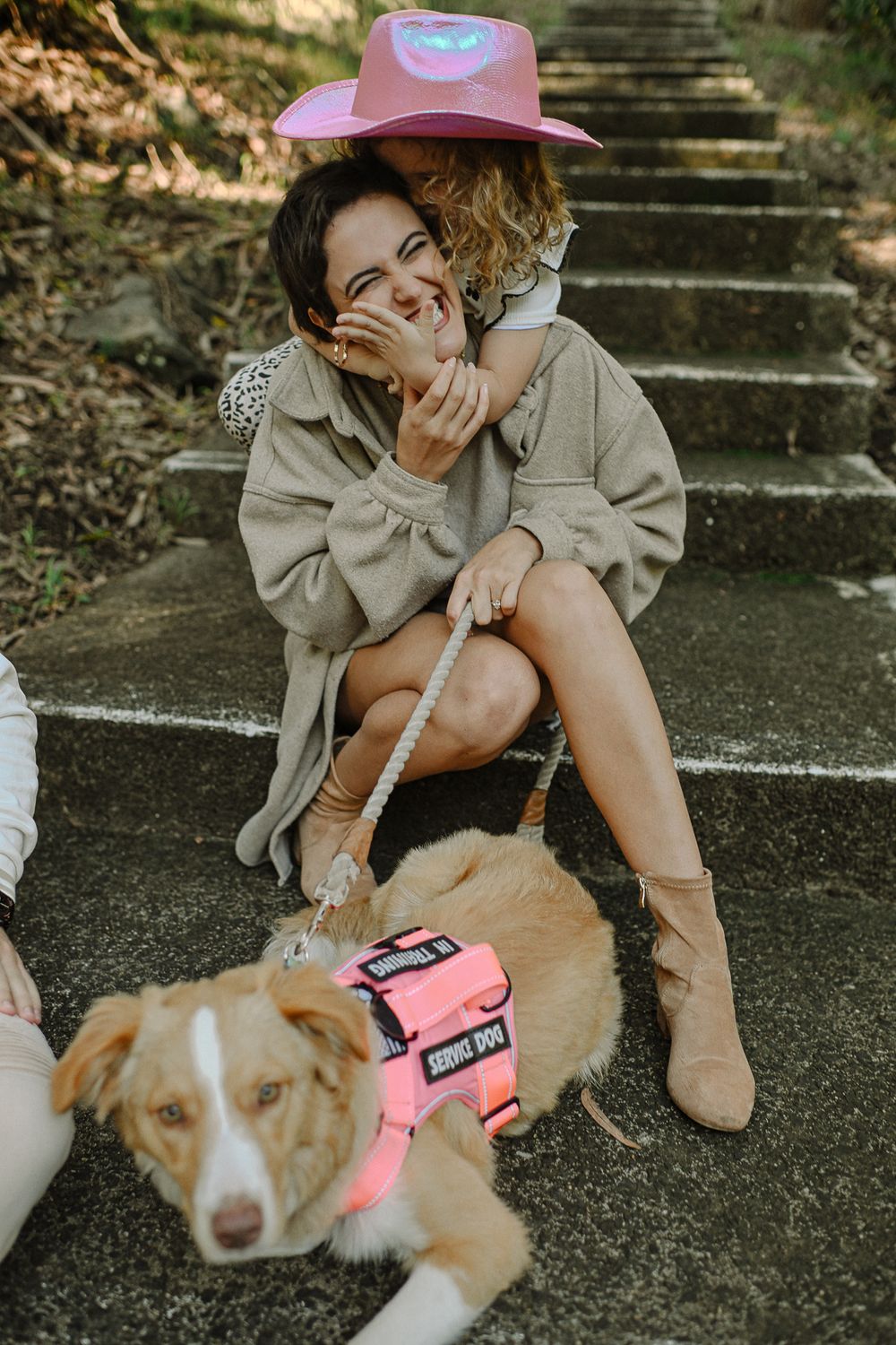 A joyful moment on stone steps with a service dog wearing a pink harness.