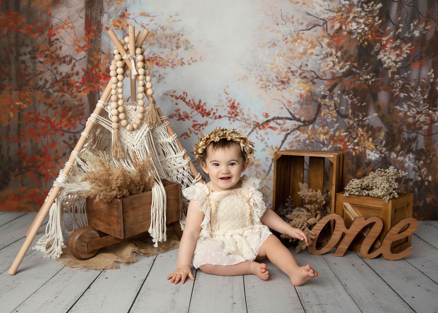 Rustic autumn themed first birthday setup with boho teepee and wooden decorations.