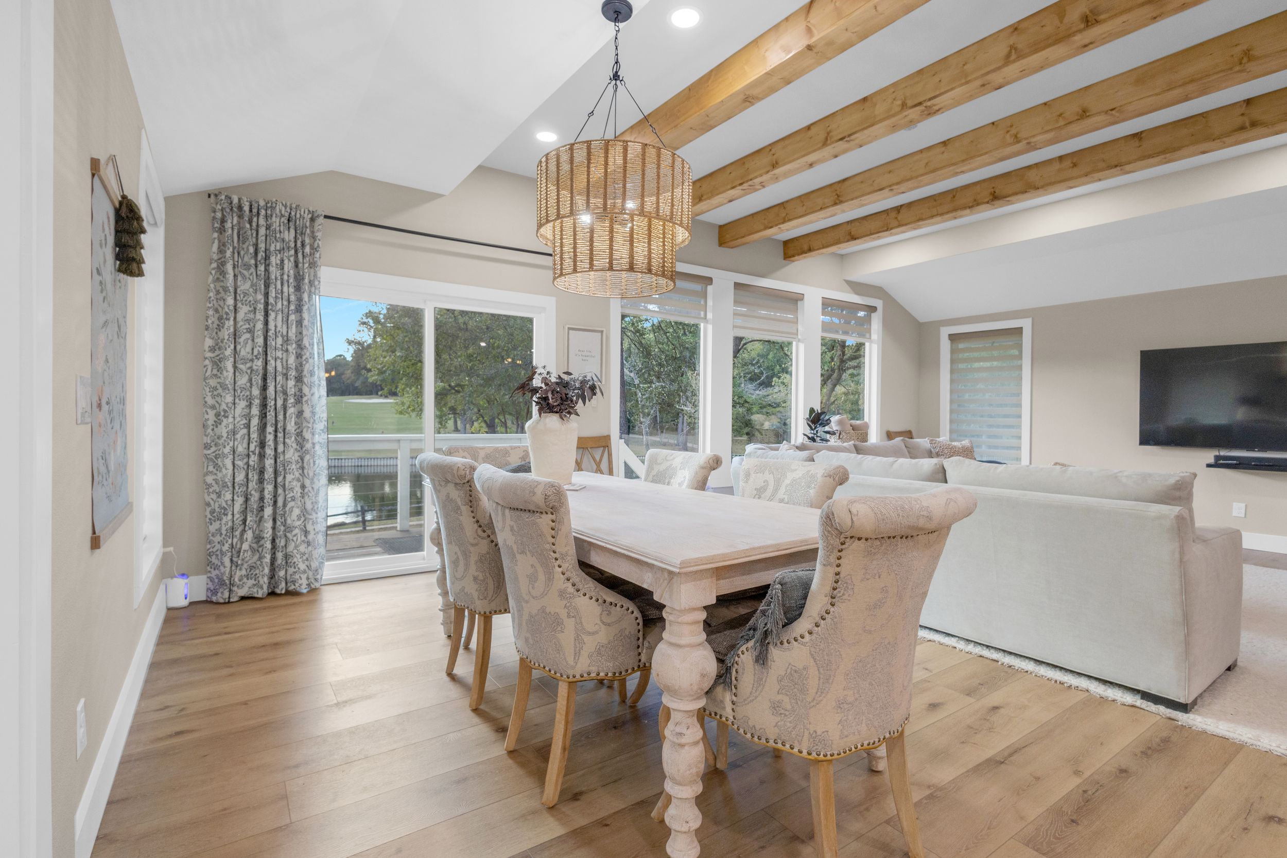 Modern open concept living room with hardwood floors, white walls, and natural light streaming through large windows.