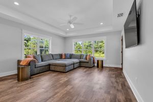 Modern living room with gray sectional sofa, hardwood floors, and large windows.