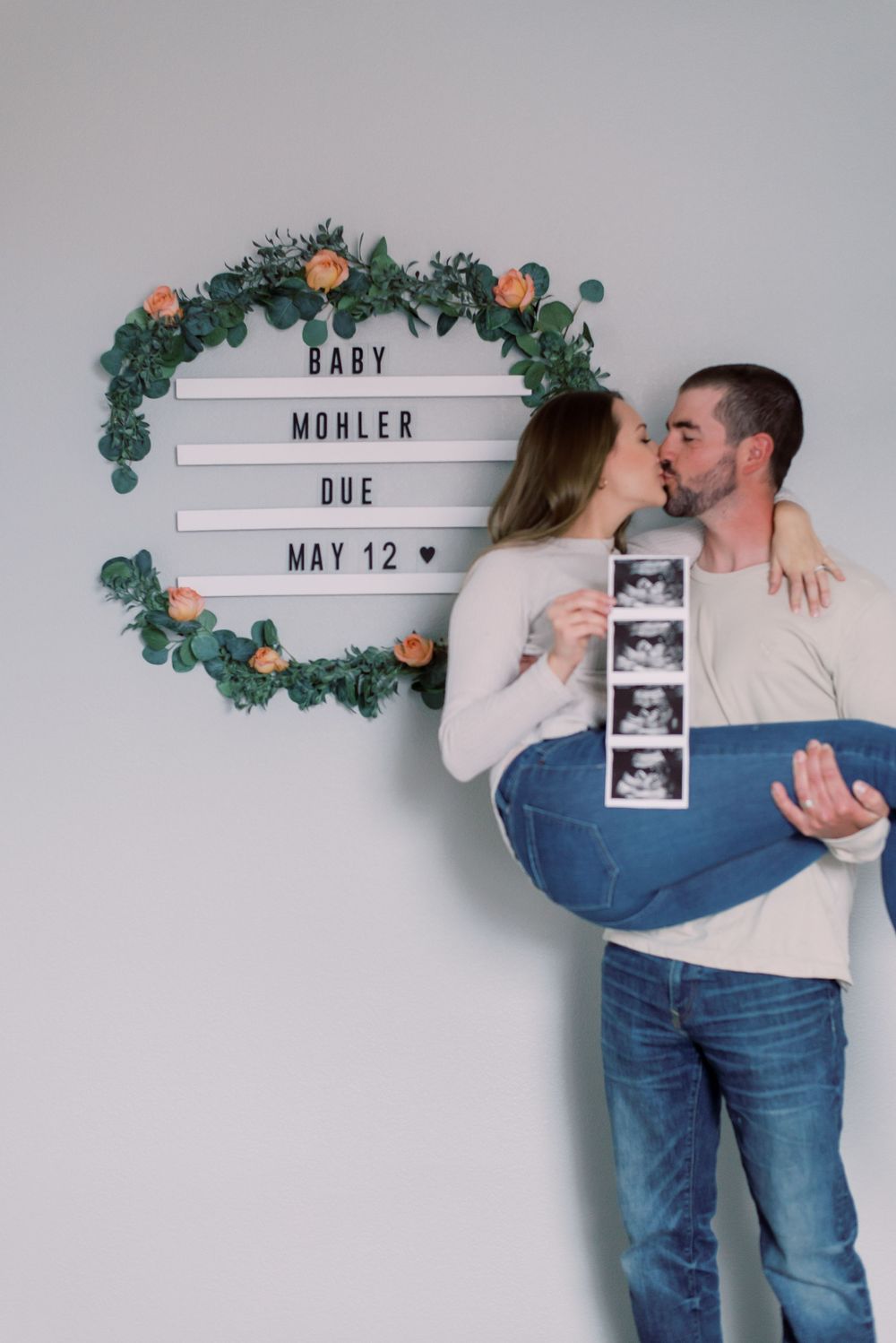 Couple embracing in a heartfelt pregnancy announcement, with roses taken at home in Columbia, MO.