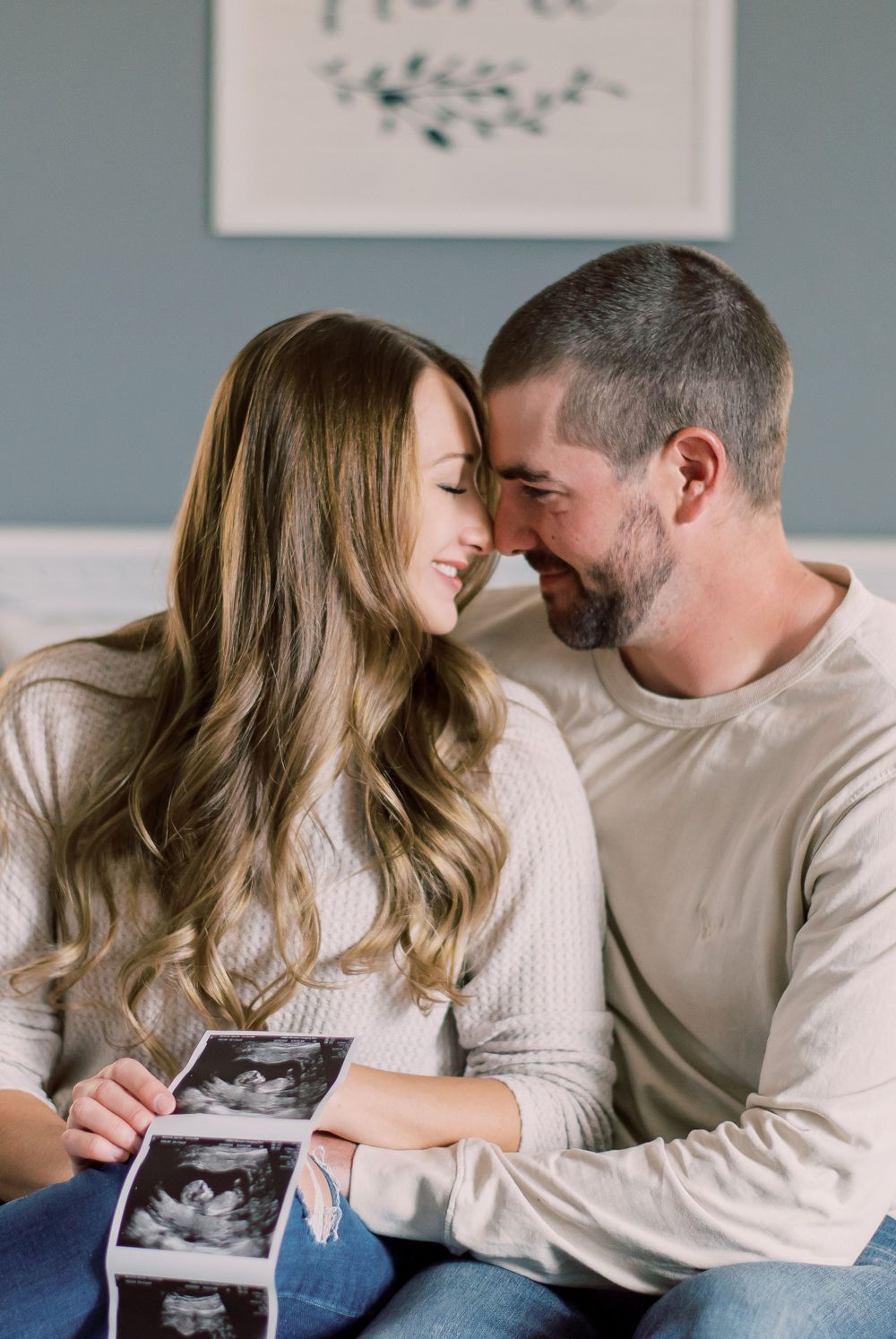 Personal pregnancy announcement photo featuring a couple surrounded by roses and their two dogs in the comfort of their home in Columbia, MO
