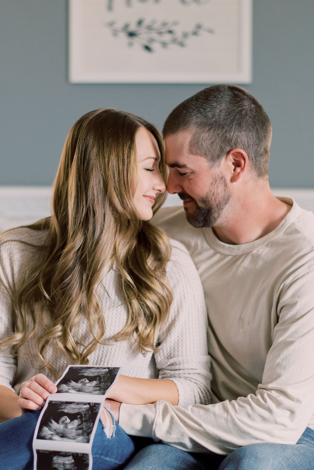 Personal pregnancy announcement photo featuring a couple surrounded by roses and their two dogs in the comfort of their home in Columbia, MO