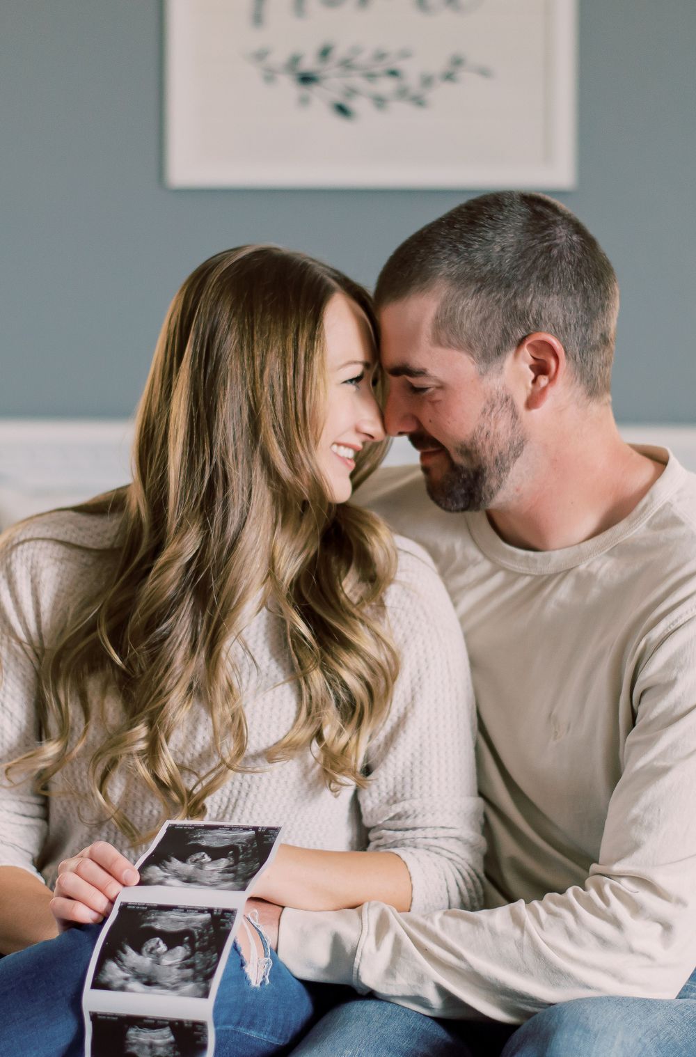 Pregnancy reveal captured in a warm, homey setting with a couple holding sonogram in Columbia, MO.