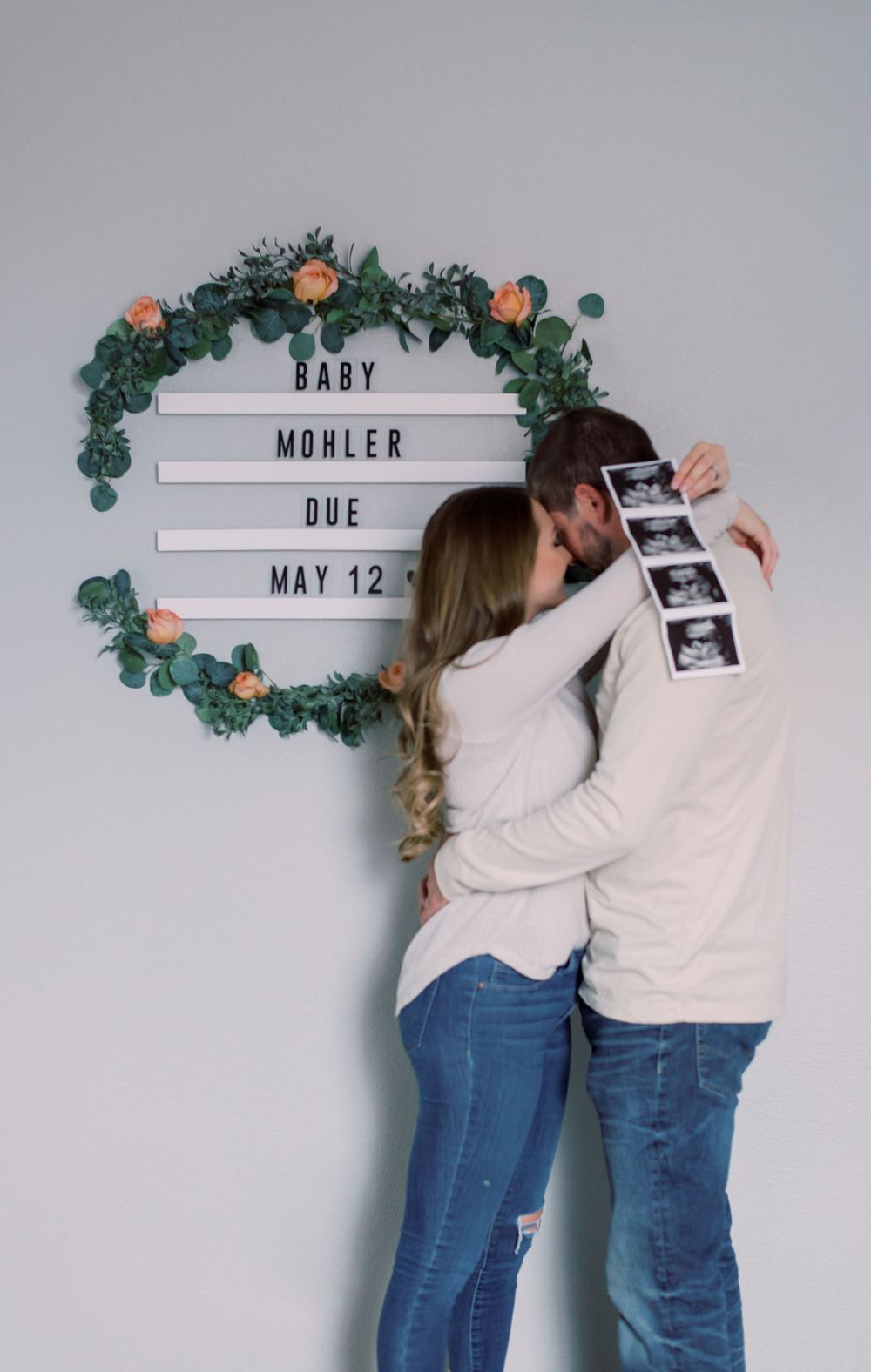 Couple in a cozy Columbia, MO home, celebrating their pregnancy announcement with roses as the backdrop.