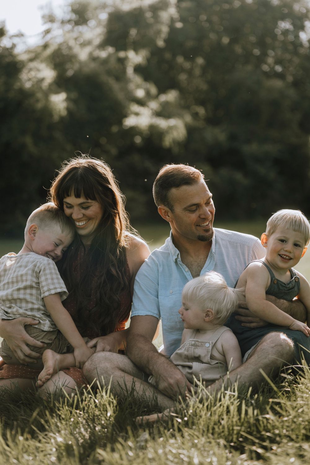 A family sitting together in a sunlit meadow during golden hour.