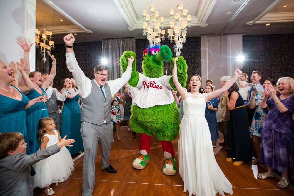 Wedding reception celebration in an elegant ballroom with chandeliers and dancing guests.