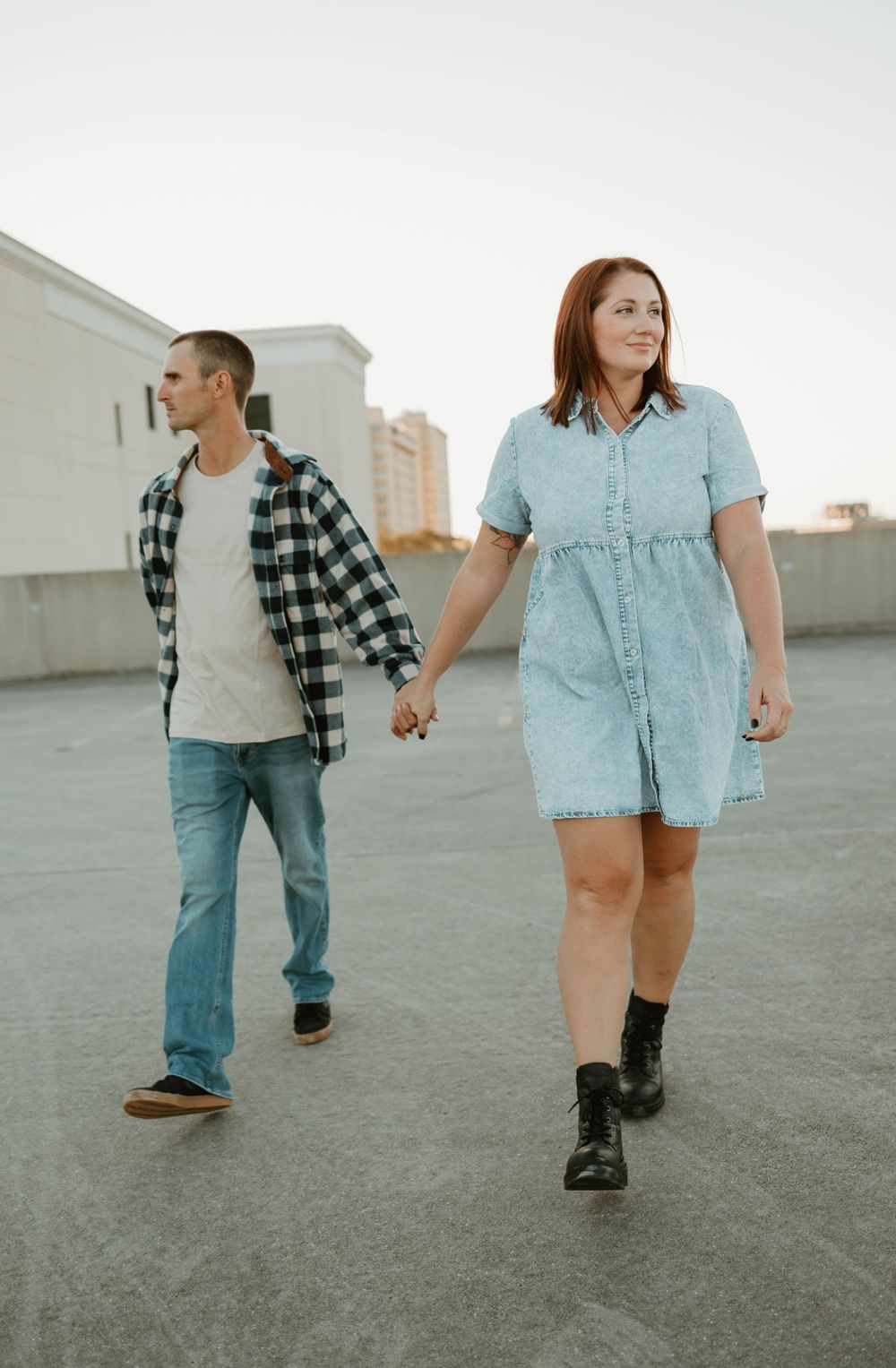 Couple walking together on a rooftop wearing casual denim and plaid outfits.