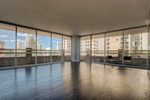 Modern high-rise condo with floor-to-ceiling windows, dark hardwood floors, and panoramic city skyline views.