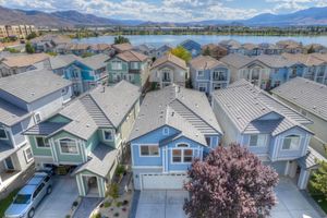 Aerial view of colorful townhomes near a lake with mountain views and tree-lined streets.