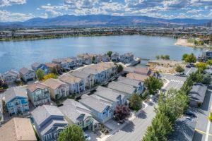 Aerial view of a lakeside community with clustered homes, tree-lined streets, and mountain views in Nevada.