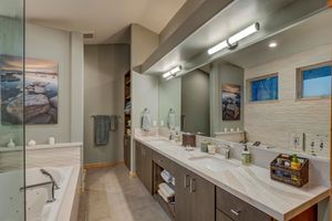Luxurious master bathroom with dual vanities, soaking tub, walk-in shower, and large mirrors.