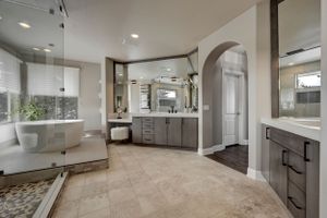 Spacious luxury bathroom with freestanding tub, dual vanity, arched doorway, and elegant tile flooring.