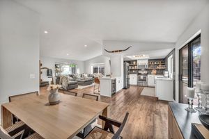 Open-concept dining and living area with hardwood floors, kitchen island, and large windows.