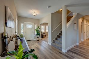 Bright open entryway with hardwood floors, staircase, arched doorways, and abundant natural light.