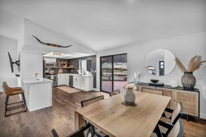 Spacious dining room with wood table, open kitchen, sliding glass doors, and modern decor.