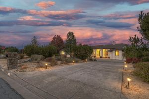 Single-story home with desert landscaping, pathway lighting, and colorful dramatic sunset sky at twilight.