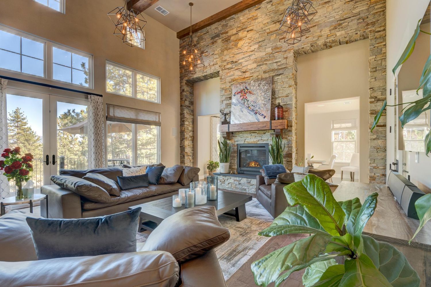 Spacious living room with stone fireplace, vaulted ceilings, leather sofas, and large windows with natural light.