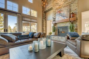 Cozy living room featuring a stone fireplace, leather sectional sofa, and candle-lit coffee table with mountain views.
