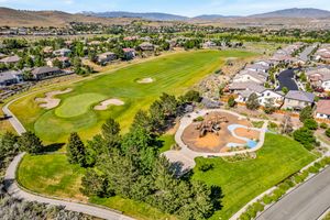 Aerial view of golf course with playground area and upscale residential neighborhood near Nevada mountains.
