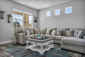 Spacious living room featuring gray sectional sofa, white coffee table, and large windows.
