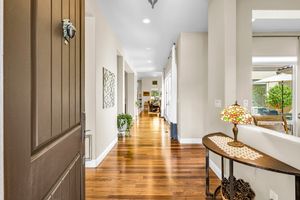 Bright open entryway with hardwood floors, neutral walls, decorative console table, and Tiffany-style lamp.