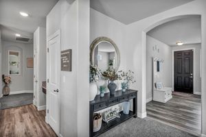 Entryway hallway with console table, round mirror, arched doorway, and hardwood floors.