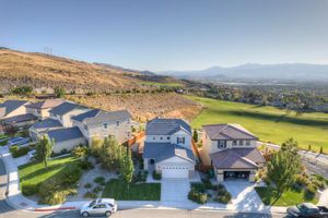 Aerial view of upscale suburban homes on a hillside with golf course and valley panorama.