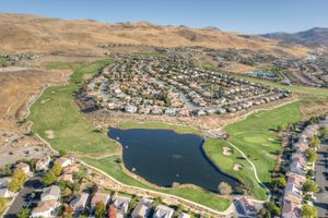 Bird's eye view of a residential golf course community featuring a large pond and hillside setting.