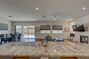 Open-concept kitchen and living area with granite counters, fireplace, and patio access.
