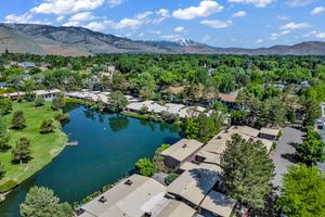 Aerial view of a lakeside community surrounded by lush trees with snow-capped mountains in the background.