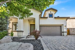 Charming two-story stucco home with stone accents, two-car garage, and decorative paver driveway.