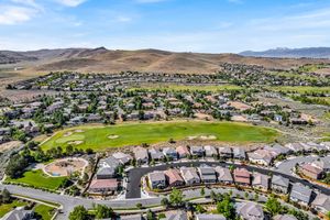 Aerial view of upscale Nevada neighborhood surrounding a green golf course with mountain range backdrop.