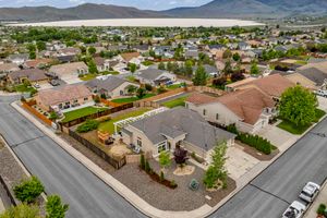 Aerial view of a suburban neighborhood with a corner home featuring a fenced yard and desert landscaping in Nevada.