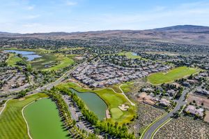 Aerial view of golf course community with ponds, lush fairways, and Nevada desert mountain scenery.