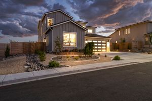 Modern two-story home with board and batten siding, desert landscaping, and three-car garage at dusk.