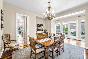 Formal dining room with wood table, chandelier, hardwood floors, and French doors leading to backyard.
