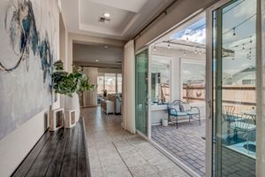 Spacious hallway with tray ceiling, large sliding glass doors, decorative art, and view to outdoor patio.