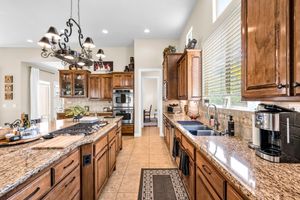 Gourmet kitchen with granite counters, rich wood cabinets, stainless appliances, and tile backsplash.