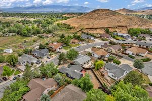Aerial view of a residential neighborhood with tree-lined streets nestled against a scenic brown hillside.