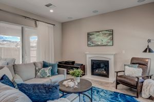 Cozy living room with gray sectional sofa, blue area rug, fireplace, and mountain views through large window.