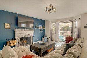 Cozy living room with bold blue accent wall, brick fireplace, large sectional sofa, and sliding glass door.